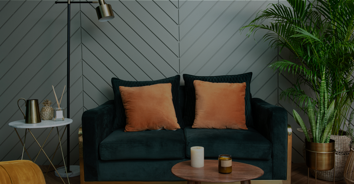 darkly lit living room with a sofa and orange pillows